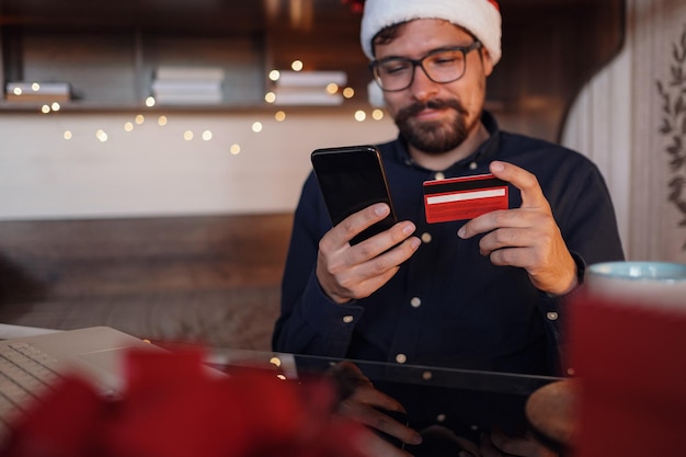 Happy man wearing Santa Claus hat holding gift or credit card