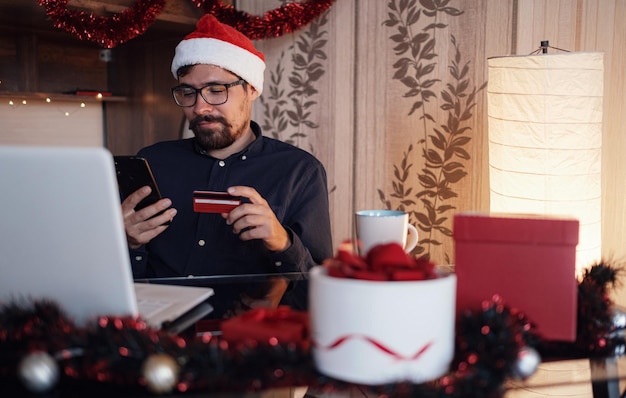 Happy man wearing Santa Claus hat holding gift or credit card