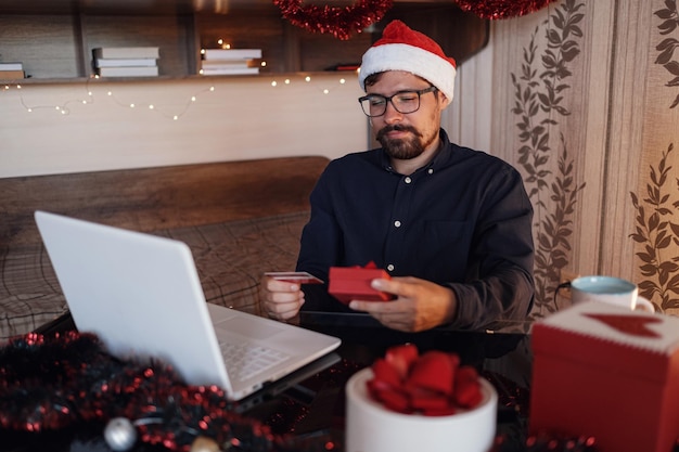 Happy man wearing Santa Claus hat holding gift or credit card