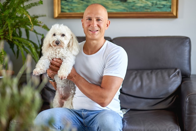 Happy man with cute dog at home on sofa