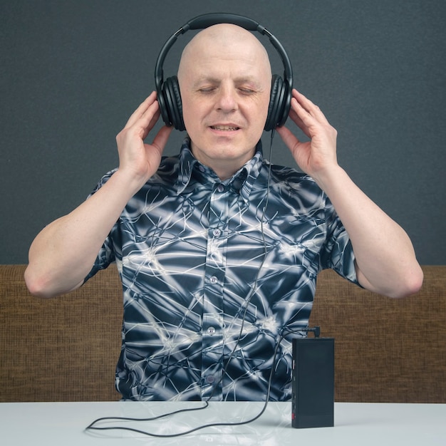 Happy man with in portable headphones listens to music using a player