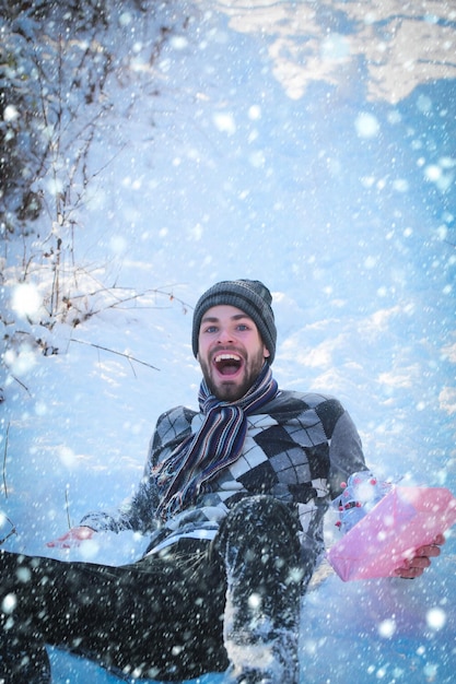 Happy man with present box lying on snow