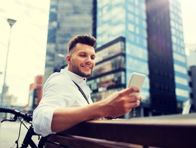 Photo happy man with smartphone and bicycle in city