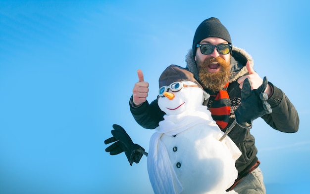 Happy man with snowman on winter outdoor background snow man for winter banner