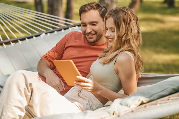 Happy man and woman looking interested in tablet