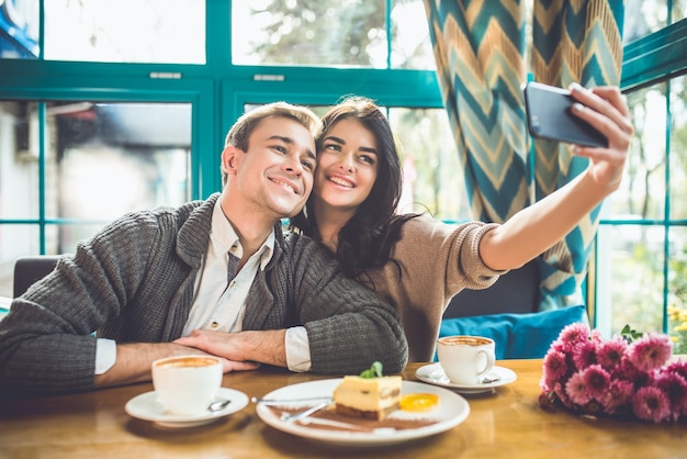 The happy man and woman make a selfie in the restaurant