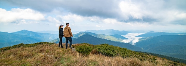 The happy man and a woman standing on the top of a mountain