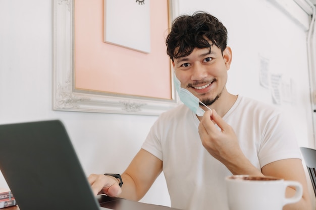 Happy man work in a cafe taking off mask and smile