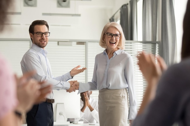 Photo happy manager boss praising old employee for good work get team appreciation acknowledgement handshaking successful worker congratulating promoting rewarding welcoming new partner respect handshake