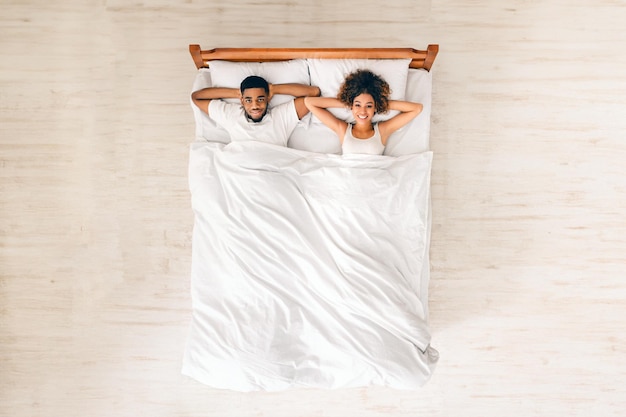 Happy married black couple resting in bed