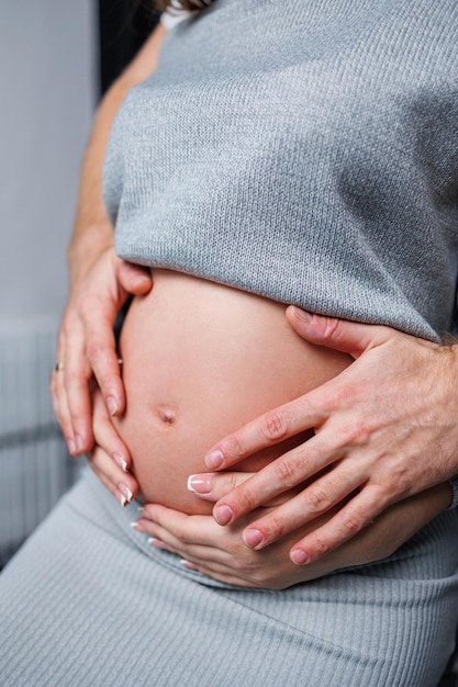 Happy married couple Pregnant woman and loving man hugging her belly on white background Sensation of movement of the baby as a couple on the belly of the pregnant woman