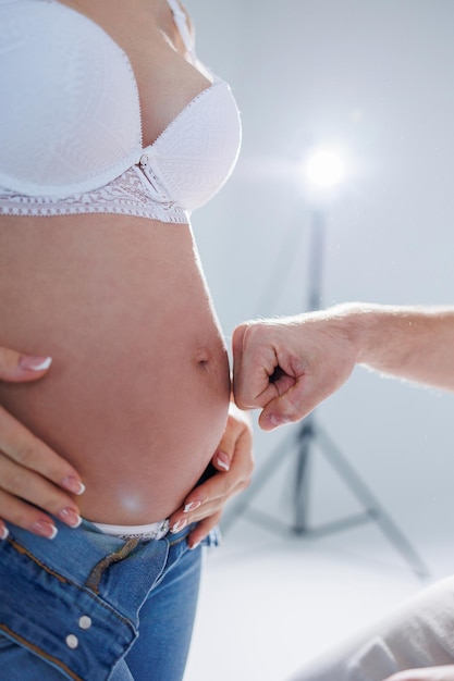 Happy married couple Pregnant woman and loving man hugging her belly on white background Sensation of movement of the baby as a couple on the belly of the pregnant woman