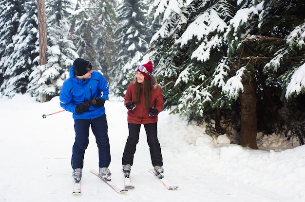 Happy married couple skiing at a ski resort in the forest