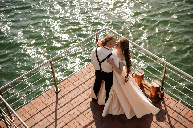 Happy married man and woman standing on the pier on the lake. Conception of the wedding