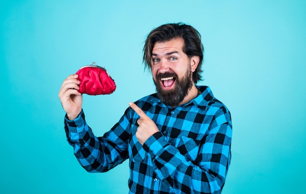 Happy mature bearded hipster man holding purse with money on blue background finance