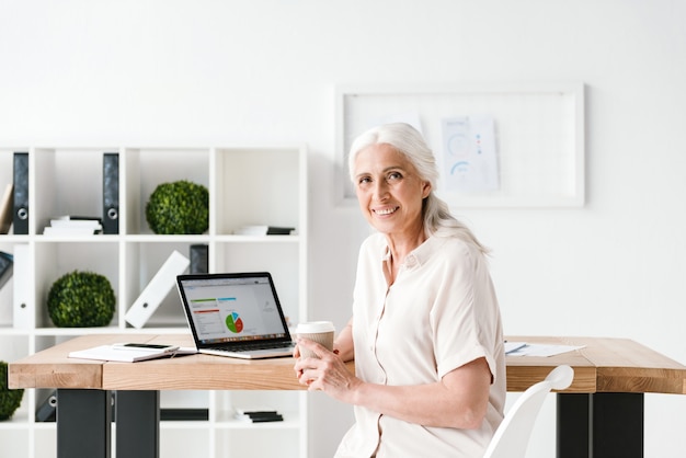 Happy mature business woman working on laptop