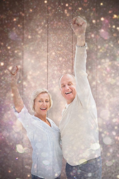 Happy mature couple cheering at camera against white snow and stars on black