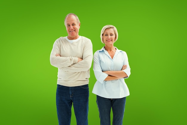 Happy mature couple smiling at camera against green vignette