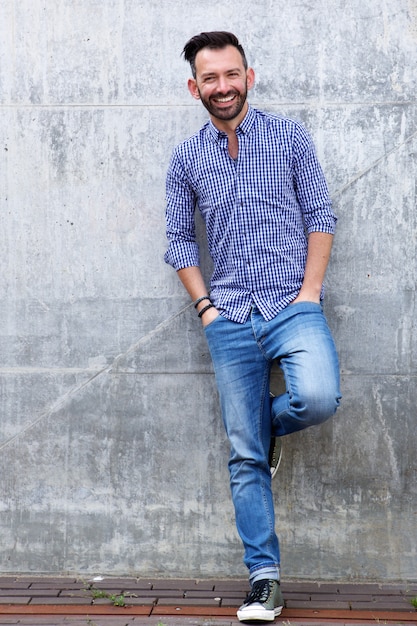 Happy mature male model posing against wall 