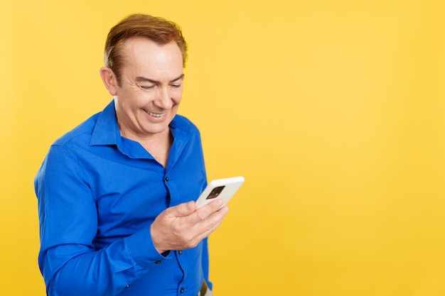 Happy mature man looking at the mobile phone