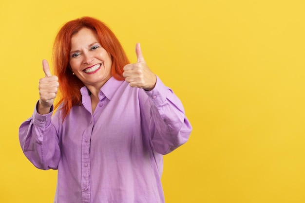 Happy mature woman gesturing agreement raising a thumb up