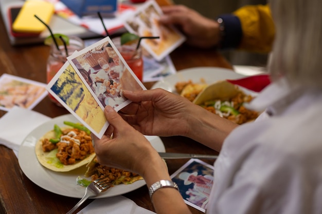 Happy memories. Woman holding in hands two photographs from her holiday looking at them during her lunch.