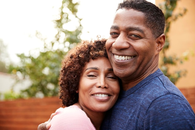 Happy middle aged black couple embracing smile to camera close up