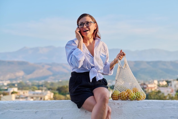 Happy middle aged woman talking on mobile phone outdoor