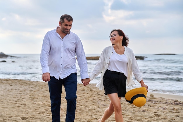 Happy middleaged couple walking together on the beach