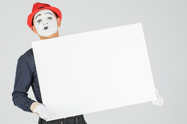 Happy MIME artist holding a blank white Board on a white background