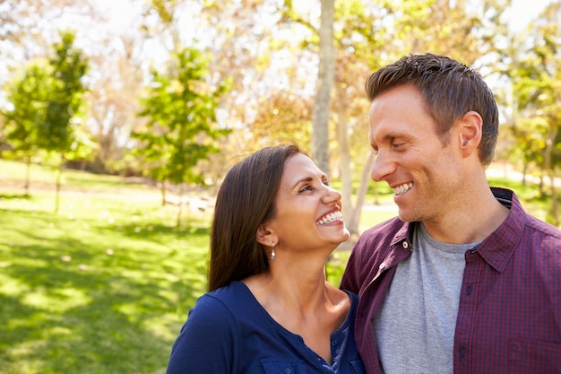 Happy mixed race couple in park looking at each other