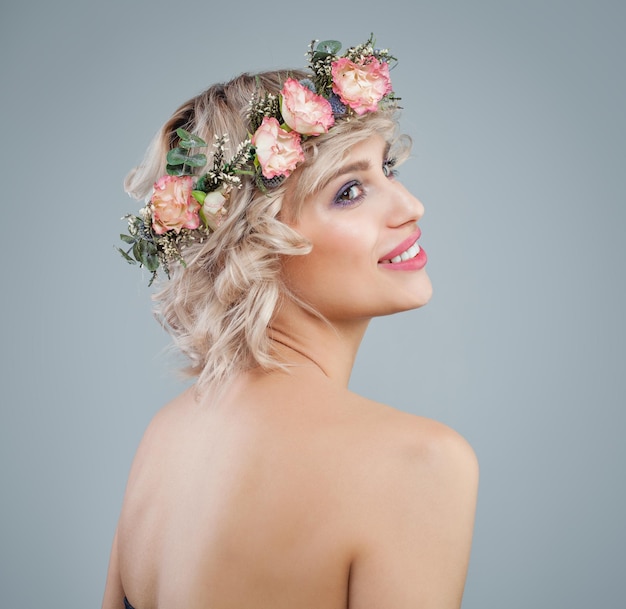 Happy model in flowers portrait Beautiful woman with short blonde curly hair and makeup on blue background