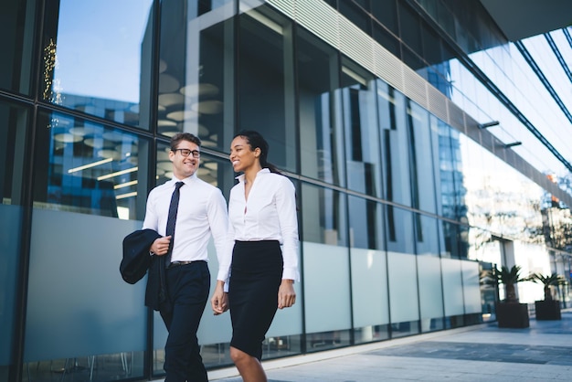 Happy modern colleagues talking on street