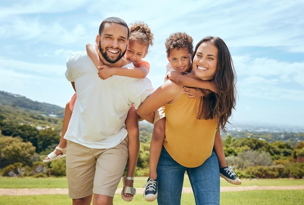 Happy mom dad and children on piggyback ride from parents in nature park for fun summer time bonding and outdoor family activity Black father mother and kids smile together while playing on grass