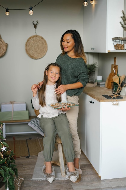 Happy mom and daughter cooked Christmas ginger cookies in the kitchen