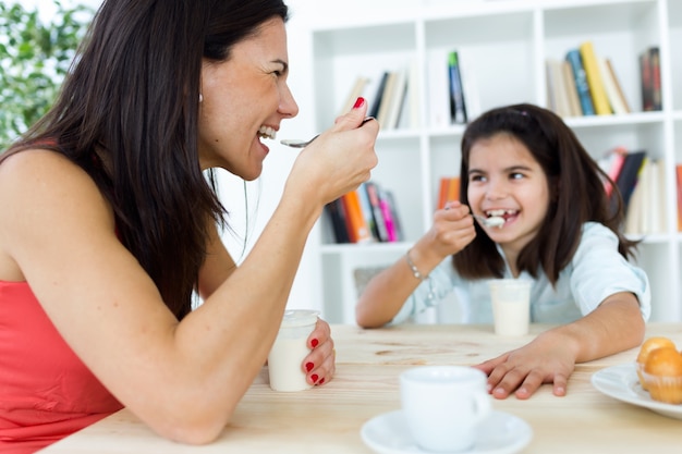 Happy mom and daughter having breakfast