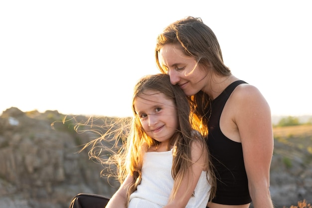 Photo happy mom and daughter relaxing on rocks in nature against the backdrop of the river happy motherhood mothers day