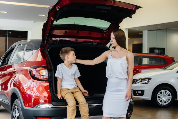 Happy mom hugs her son after buying a new car at a car dealership