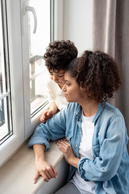 Happy mom looking on the window with her son