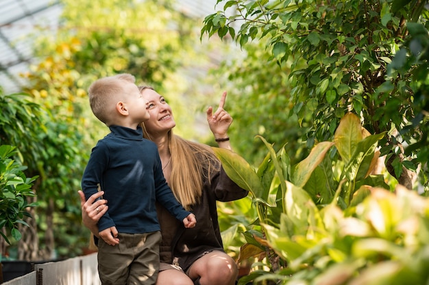 Happy mom and son look at plants in the greenhouse