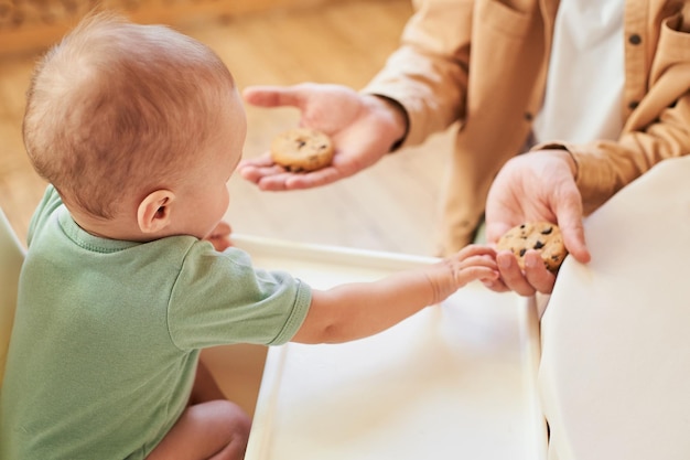 Happy moment dad feeds toddler baby cookies