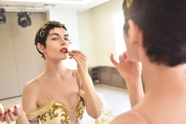 Happy Morning An attractive young woman ballerina looks at herself in the mirror and put lipstick on her lips