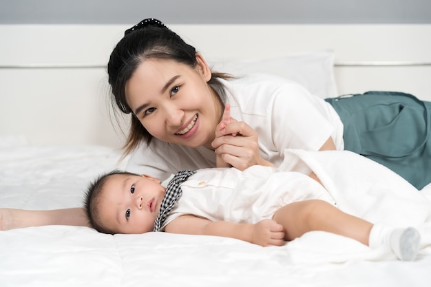 Happy mother and baby lying on a bed at home