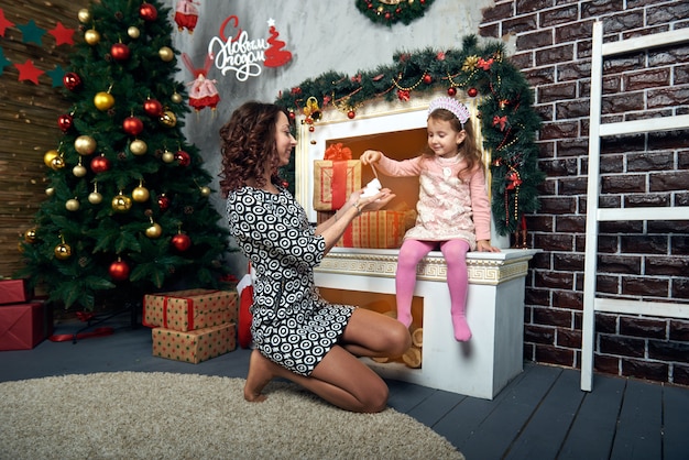 Happy mother and daughter by the fireplace for winter vacation. Christmas eve and new year's eve.