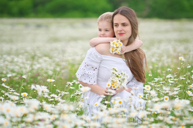 Happy mother and daughter in camomile meadow