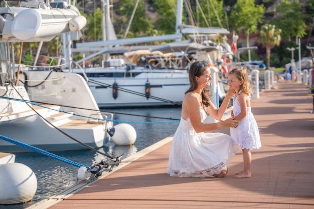 Happy mother and daughter child having fun on luxury yachts on background in marina family travel li