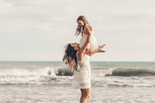 Happy mother and daughter enjoying sunny day on the beach