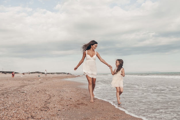 Happy mother and daughter enjoying sunny day on the beach