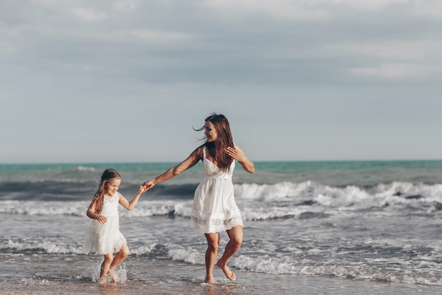 Happy mother and daughter enjoying sunny day on the beach