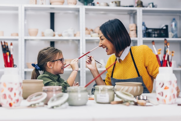 Happy mother and daughter enjoying together in making clay pottery.